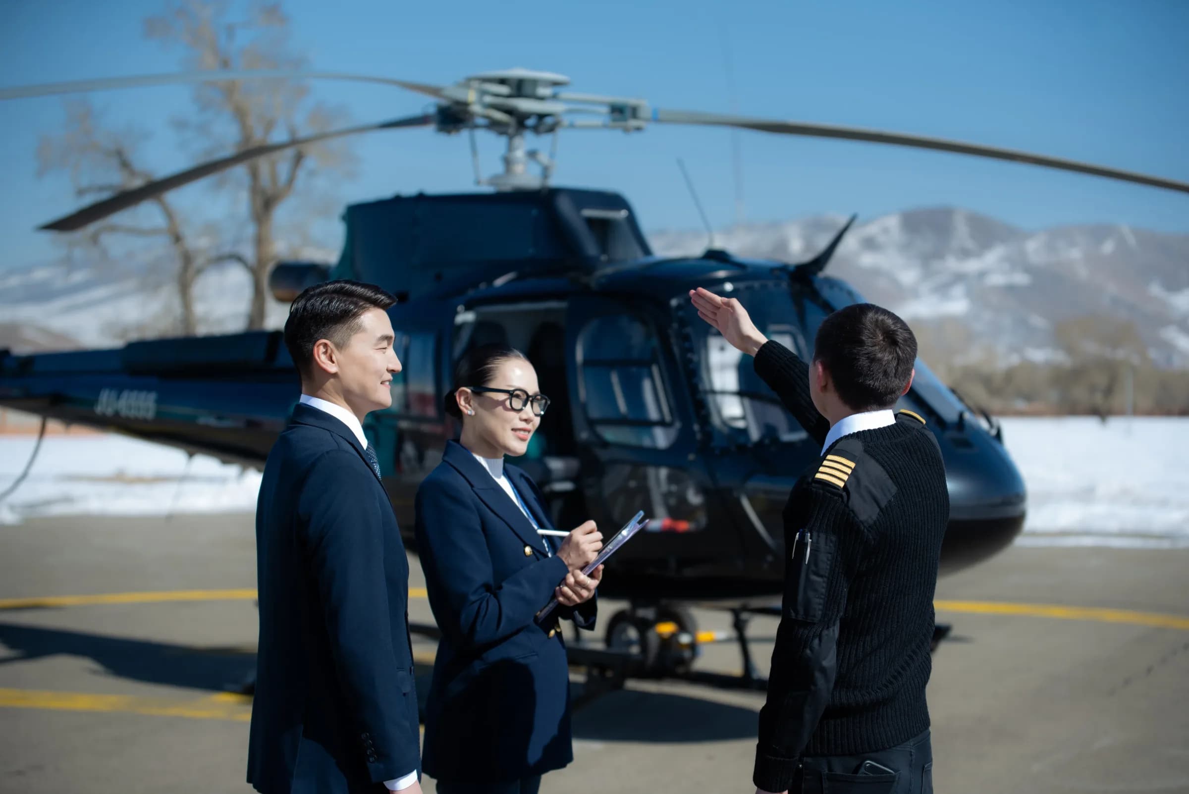 Pilot briefing two Insurco corporate advisors next to a helicopter
